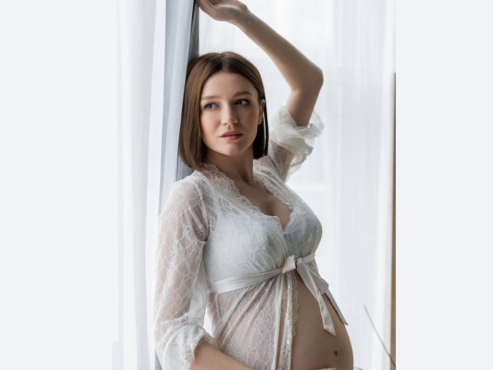 pregnant woman posing by the curtains